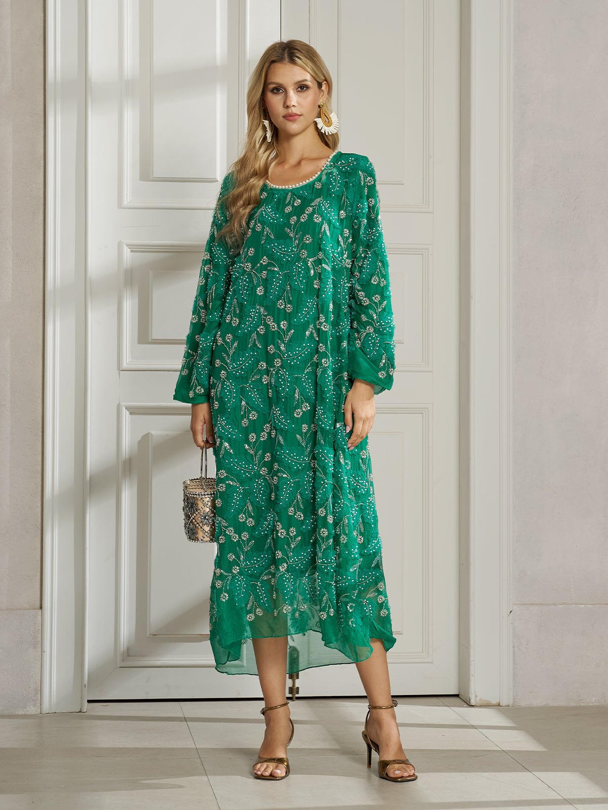 A woman indoors wears the Social Queen 100% Silk Beaded Embroidery Dress with long sleeves, holding a small handbag and pairing it with heeled sandals and large earrings.