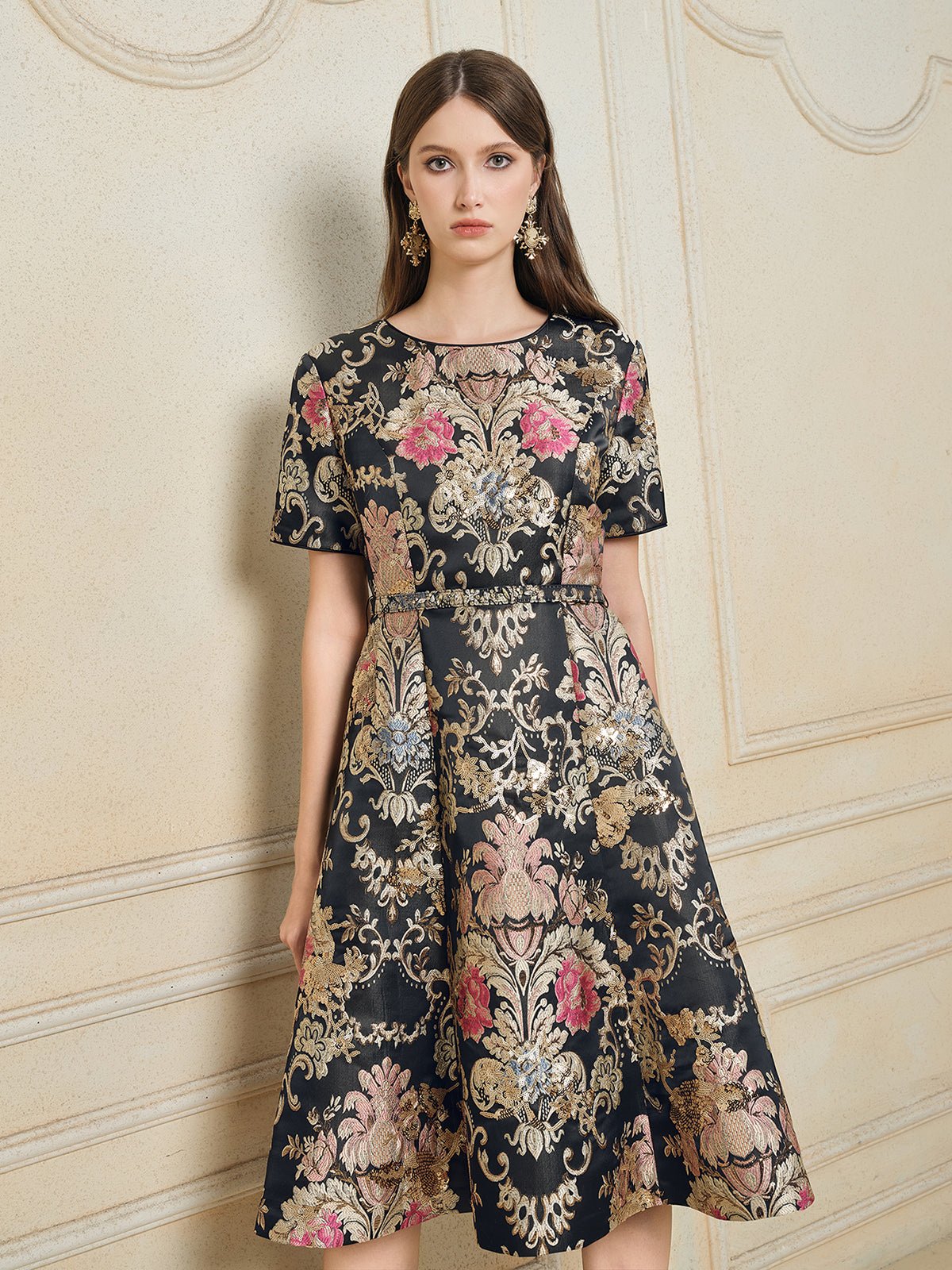 A woman stands against a textured beige wall wearing the Social Queen 100% Silk Jacquard Satin Gold Embroidered Floral Dress.