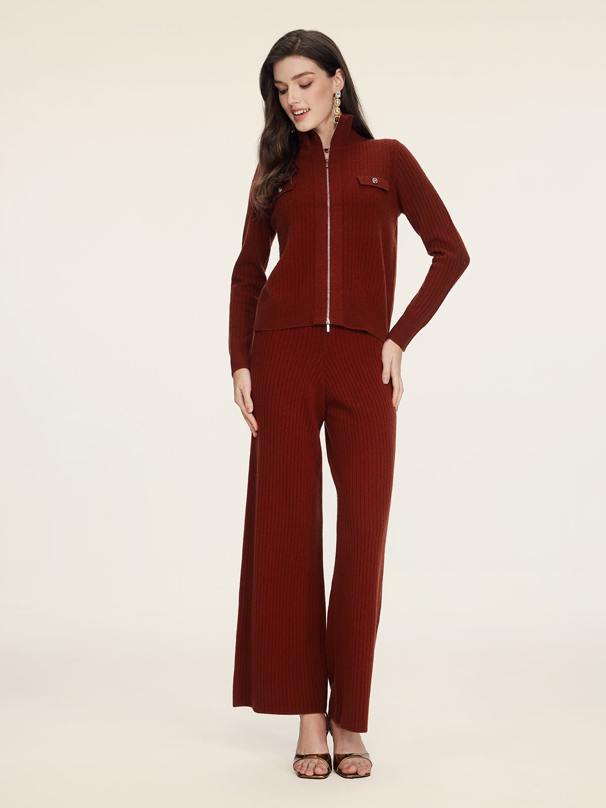 A woman wearing Social Queen 100% Wool Knit Elastic Trousers and a matching rust ribbed zip-up jacket stands against a plain light background.
