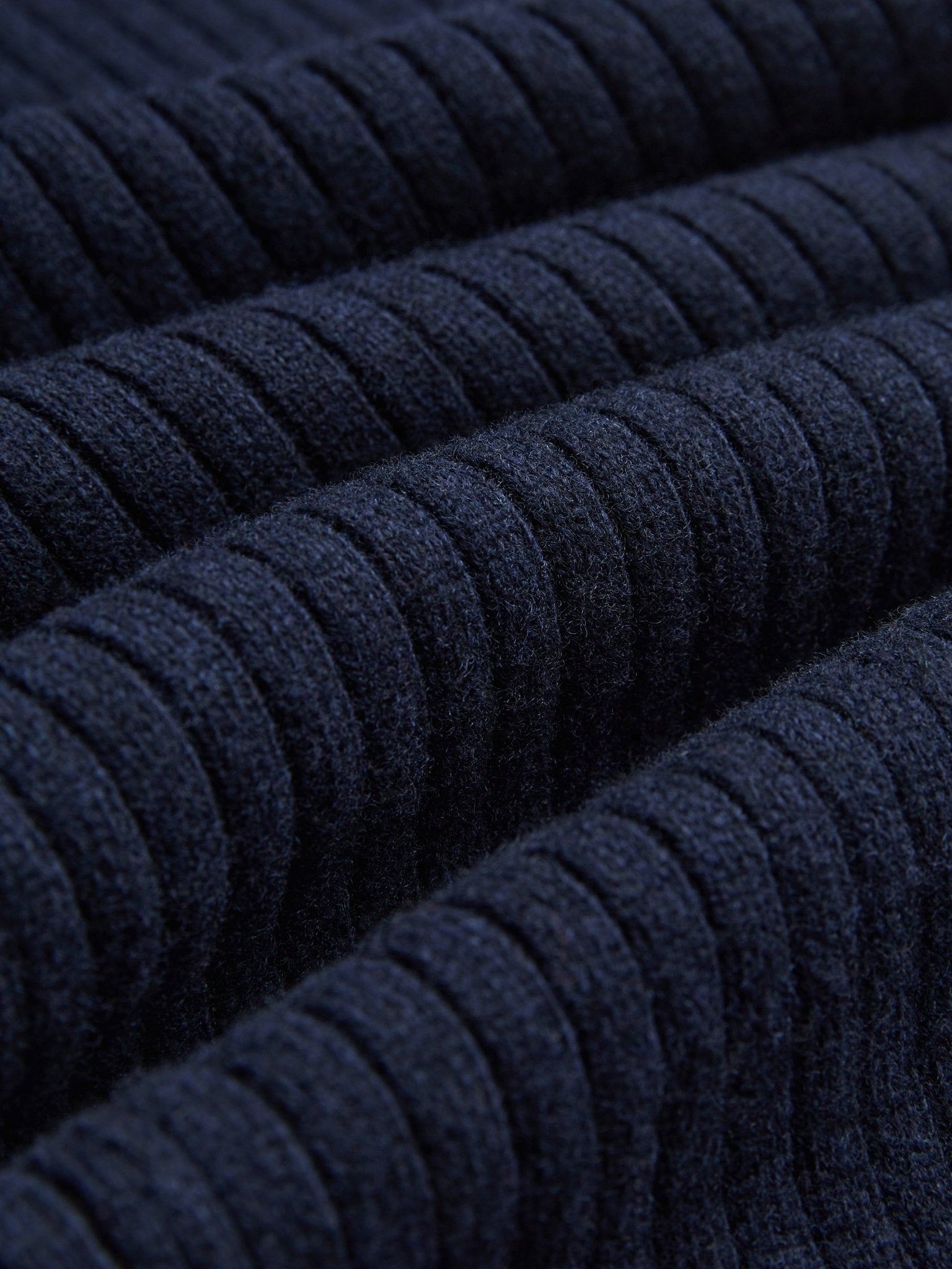 Close-up of dark blue, horizontally ribbed fabric from Social Queen's 100% Wool Knit Elastic Trousers, featuring evenly spaced textured lines and an elastic waistband.