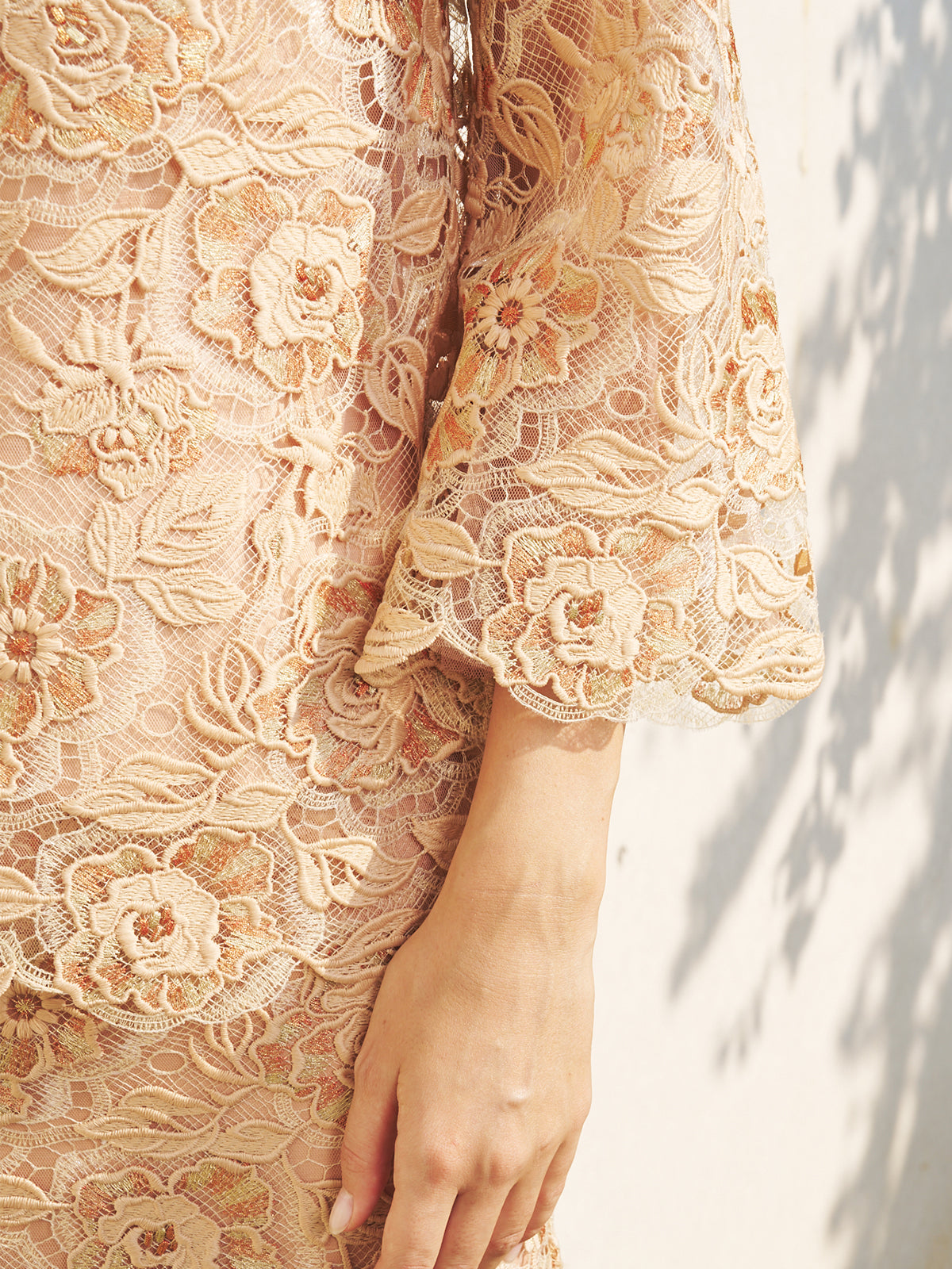 Close-up of a person wearing the Floral Embroidered Lace Top with Beaded Details by Social Queen, highlighting the intricate sleeve embroidery and delicate lace against a softly lit background.