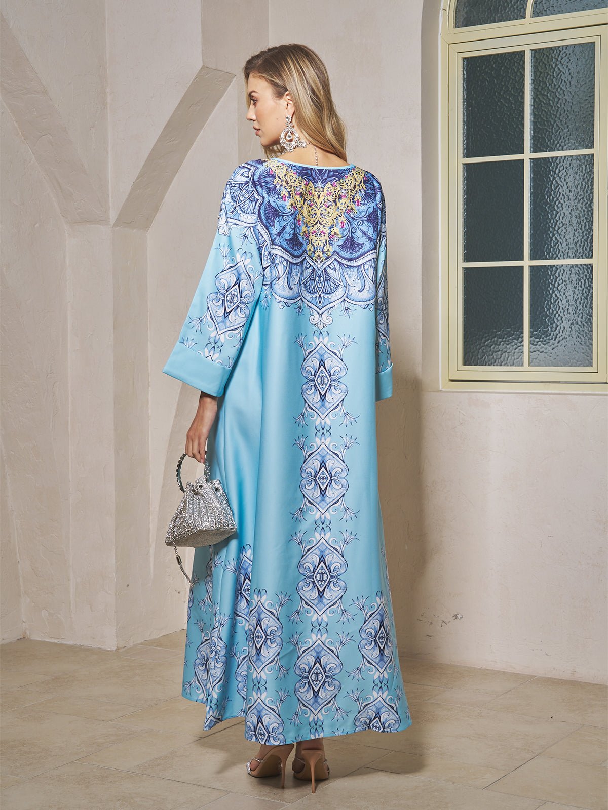 A woman in the Social Queen Beaded Baroque A-Line Dress, featuring a striking blue baroque print—ideal for resort wear.