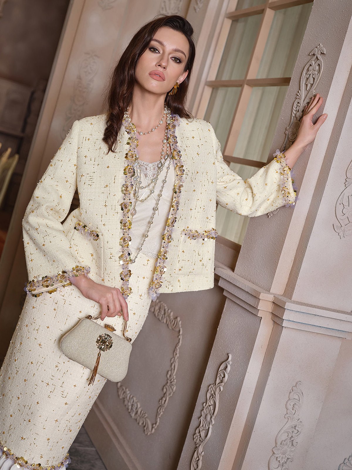 A woman stands indoors wearing the Social Queen Beaded Floral Embroidered Tweed Jacket in cream, paired with a matching handbag and layered necklaces.