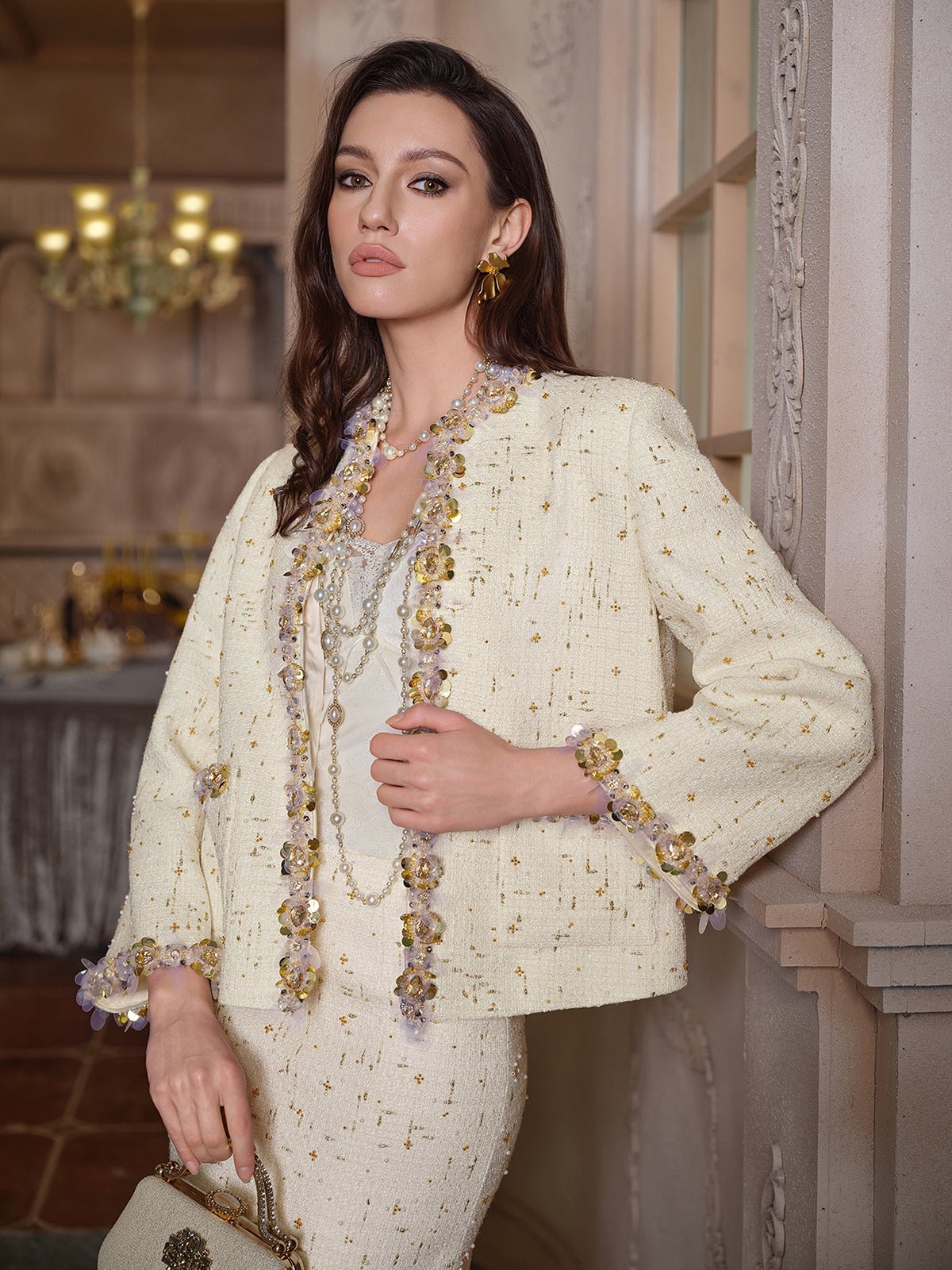 A woman stands indoors wearing the Social Queen Beaded Floral Embroidered Tweed Jacket, paired with layered necklaces and a handbag.