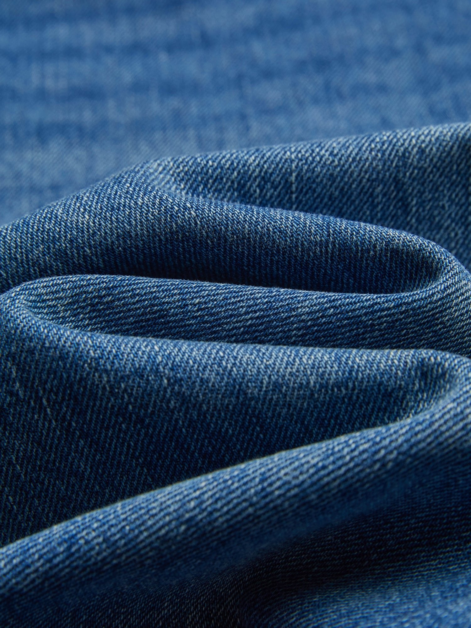 Close-up of Colorblock Floral Embroidery Jeans by Social Queen, showing blue denim with visible weave, folds, and hand-distressed details.