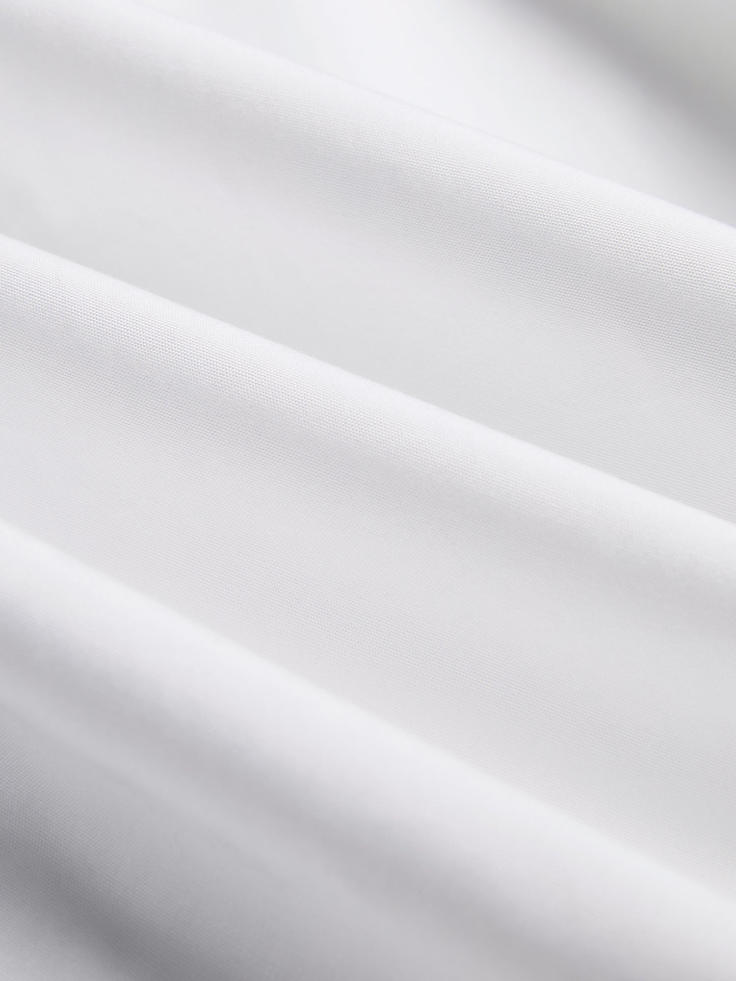 Close-up of the Cropped Embroidered Lace Panel Blouse by Social Queen, showing smooth white fabric with gentle folds and delicate hand-stitched lace accents.