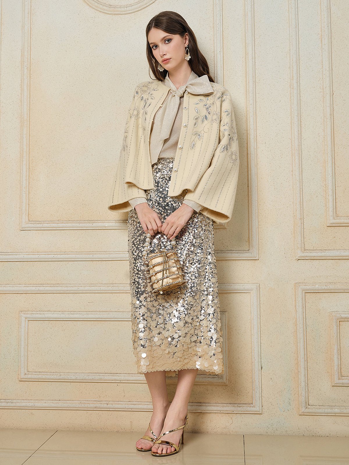 A woman stands indoors against a decorative wall, wearing the Social Queen Crystal Leaf Embroidered Wool Coat.
