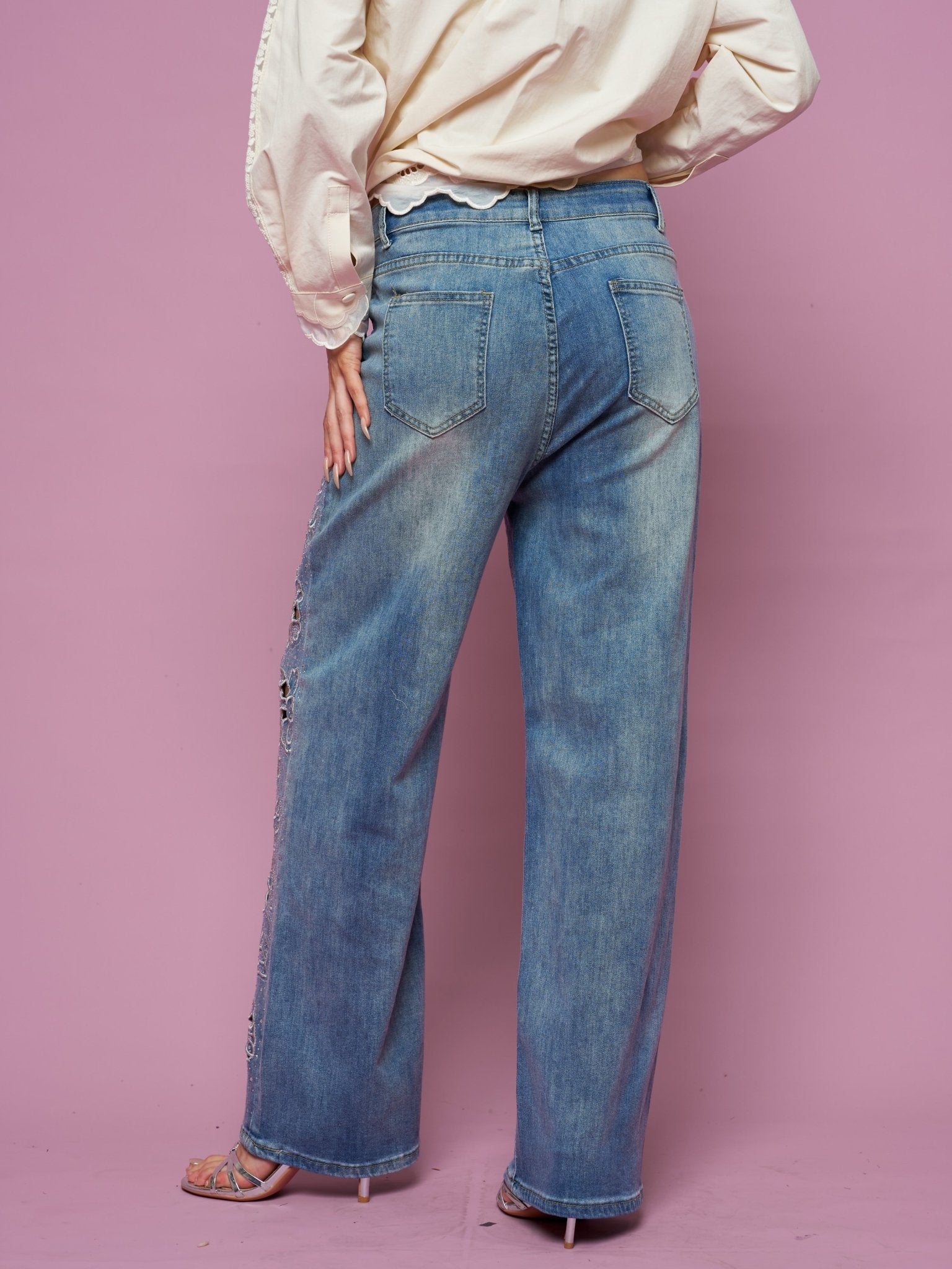 Person shown from the back, wearing Social Queen Cutout Embroidered Rhinestone Jeans and a beige long-sleeve top, standing against a pink background.
