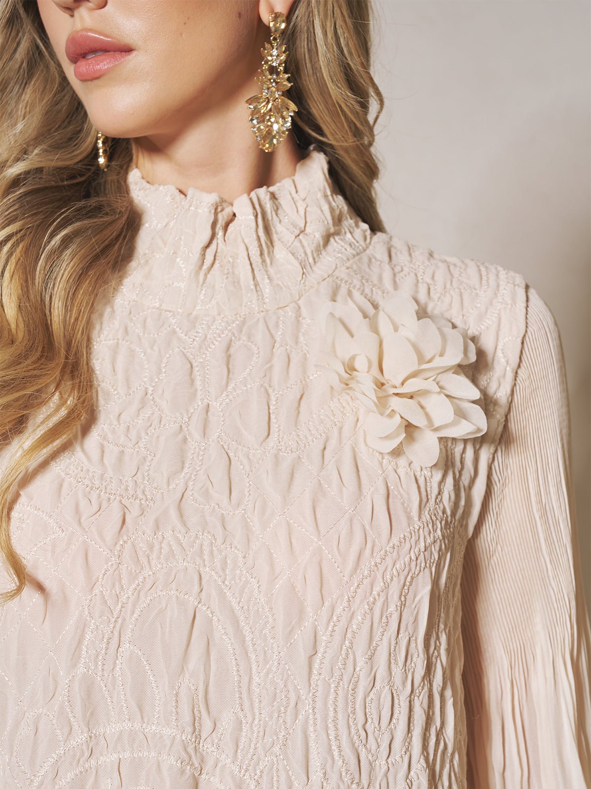 A woman wears the Social Queen Floral Appliqué Embroidered Ruffle Dress with a high ruffled collar, large floral shoulder appliqué, and gold floral earrings.