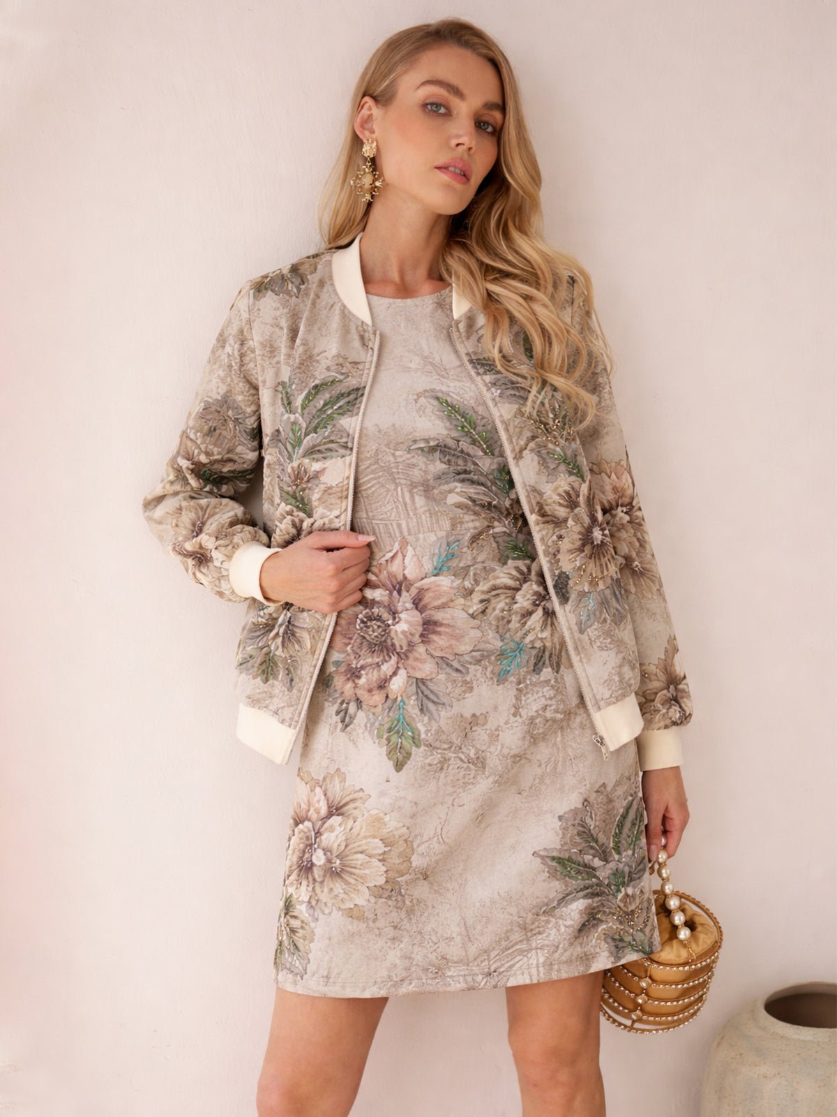 A woman stands against a light background wearing the Social Queen Floral Embroidered Jacquard Jacket over a light floral dress, holding a round woven handbag with pearl accents.