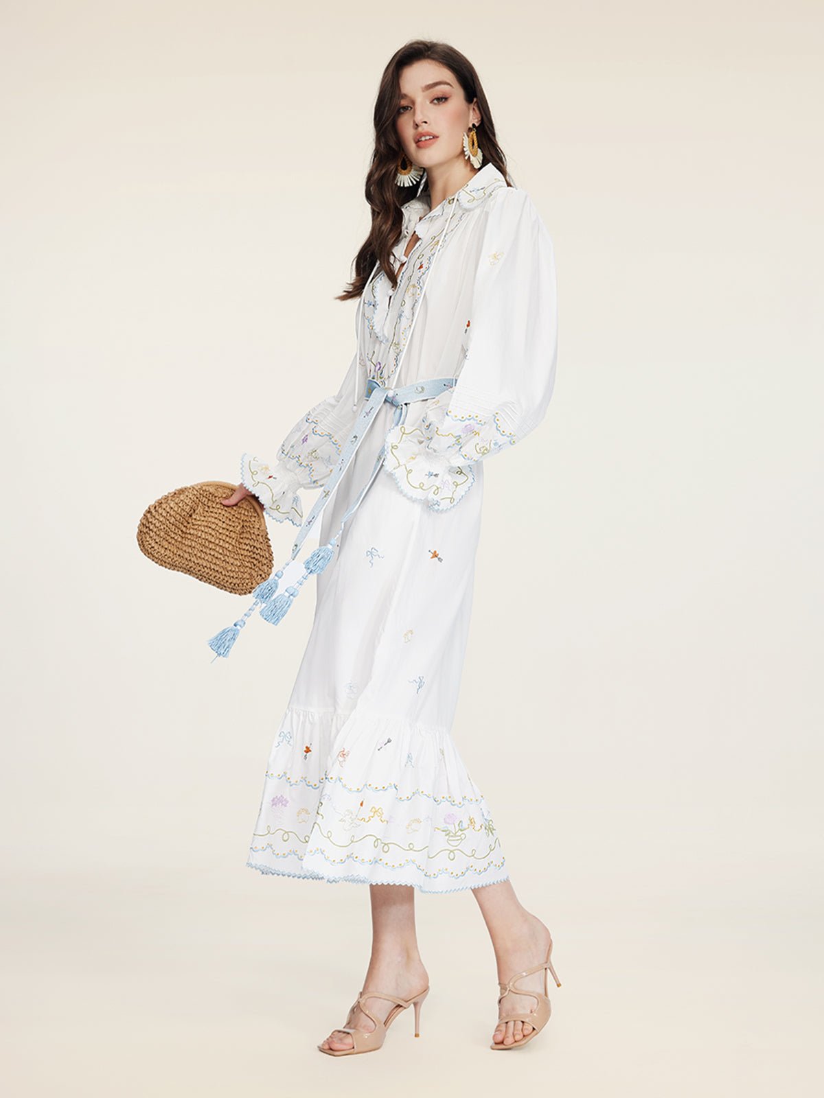 Woman in side profile wears the Social Queen Floral Embroidered Lantern Sleeve Dress with a blue belt, paired with a woven bag, beige heels, and statement earrings for a chic summer look.