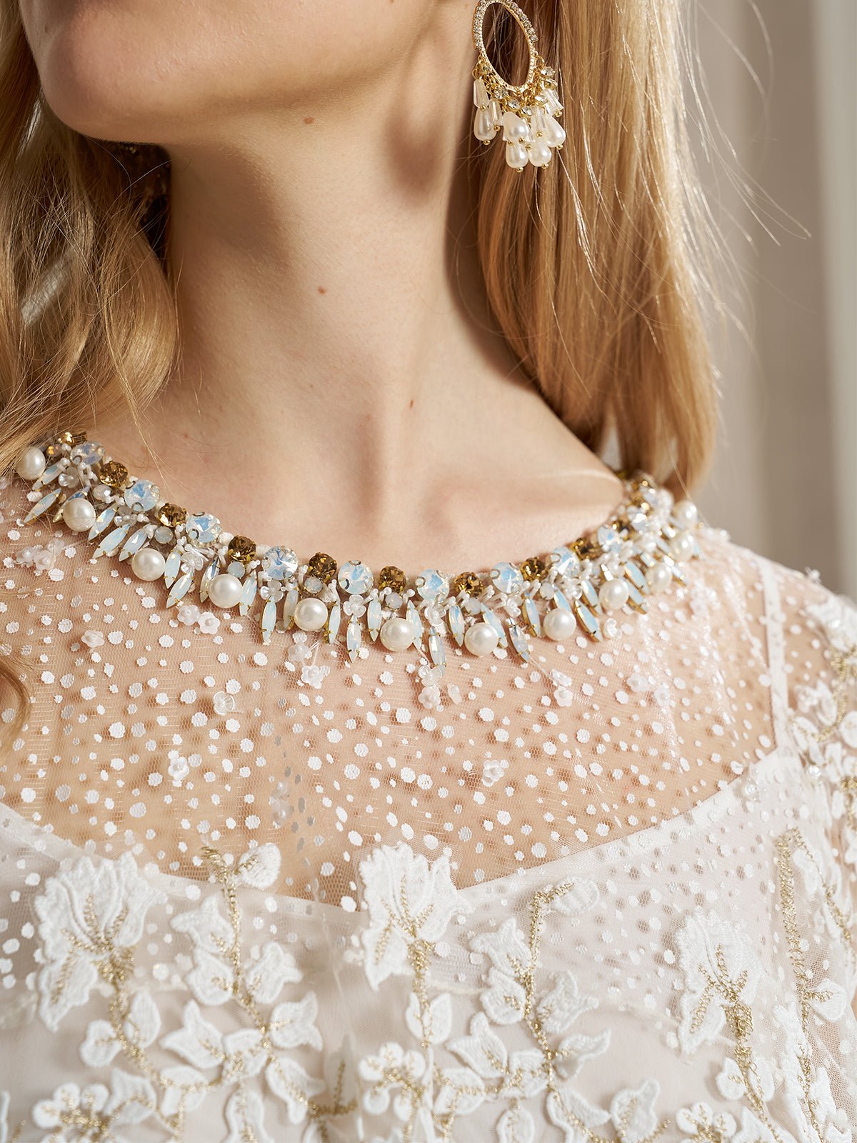 Close-up of a woman wearing the Social Queen Floral Embroidered Sheer Overlay Top with a beaded neckline, paired with a dangling earring.