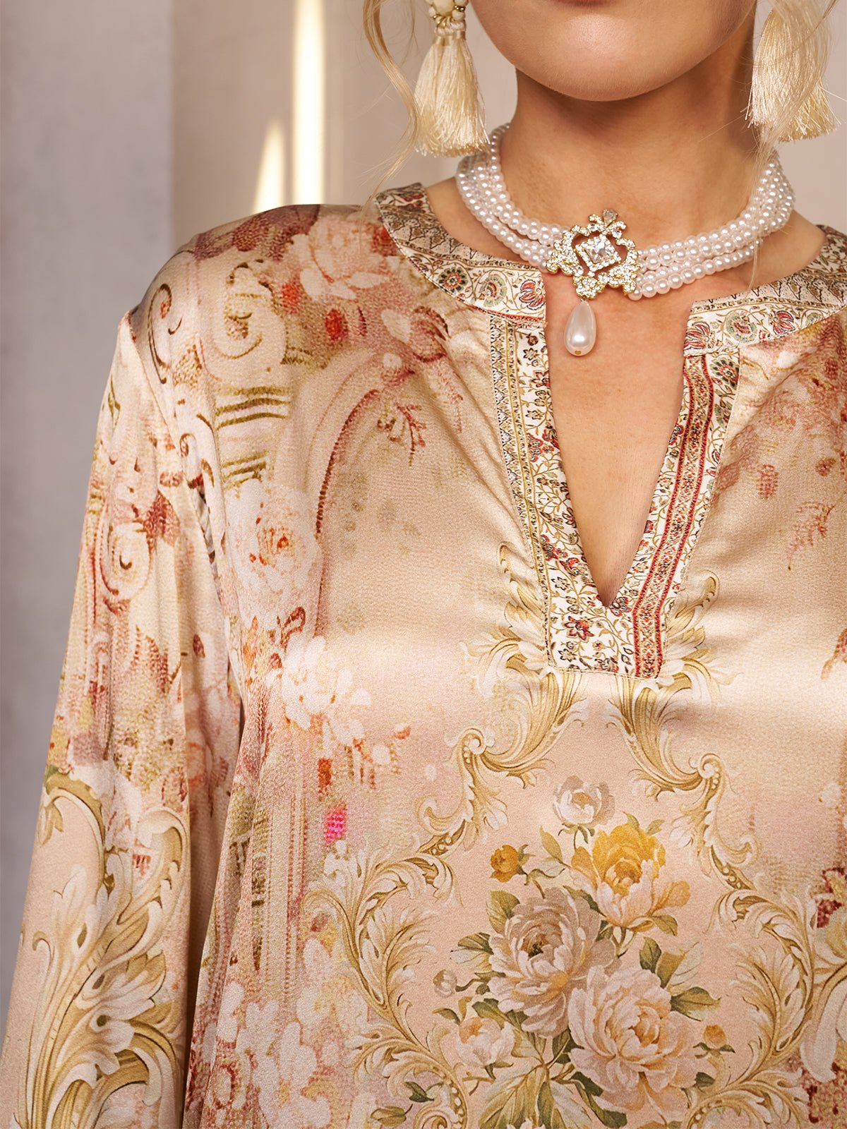 A woman wearing the Social Queen Garden Print Silk Dress with Lace Trim and a layered pearl necklace—an elegant choice for a wedding guest.
