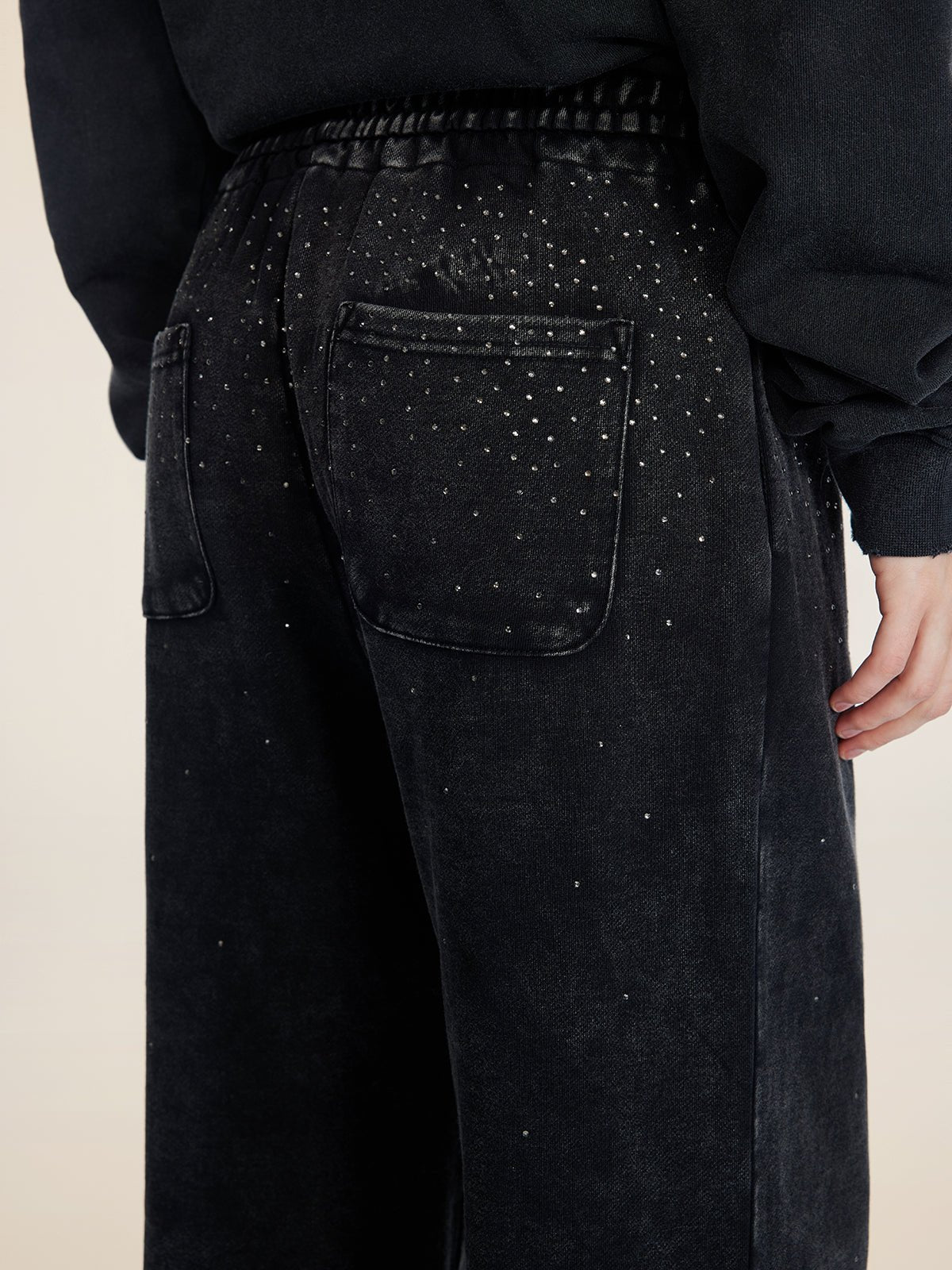 A person wearing Social Queen Gradient Rhinestone Wide-Leg Pants featuring an elastic waist, back pockets, and scattered rhinestone embellishments.