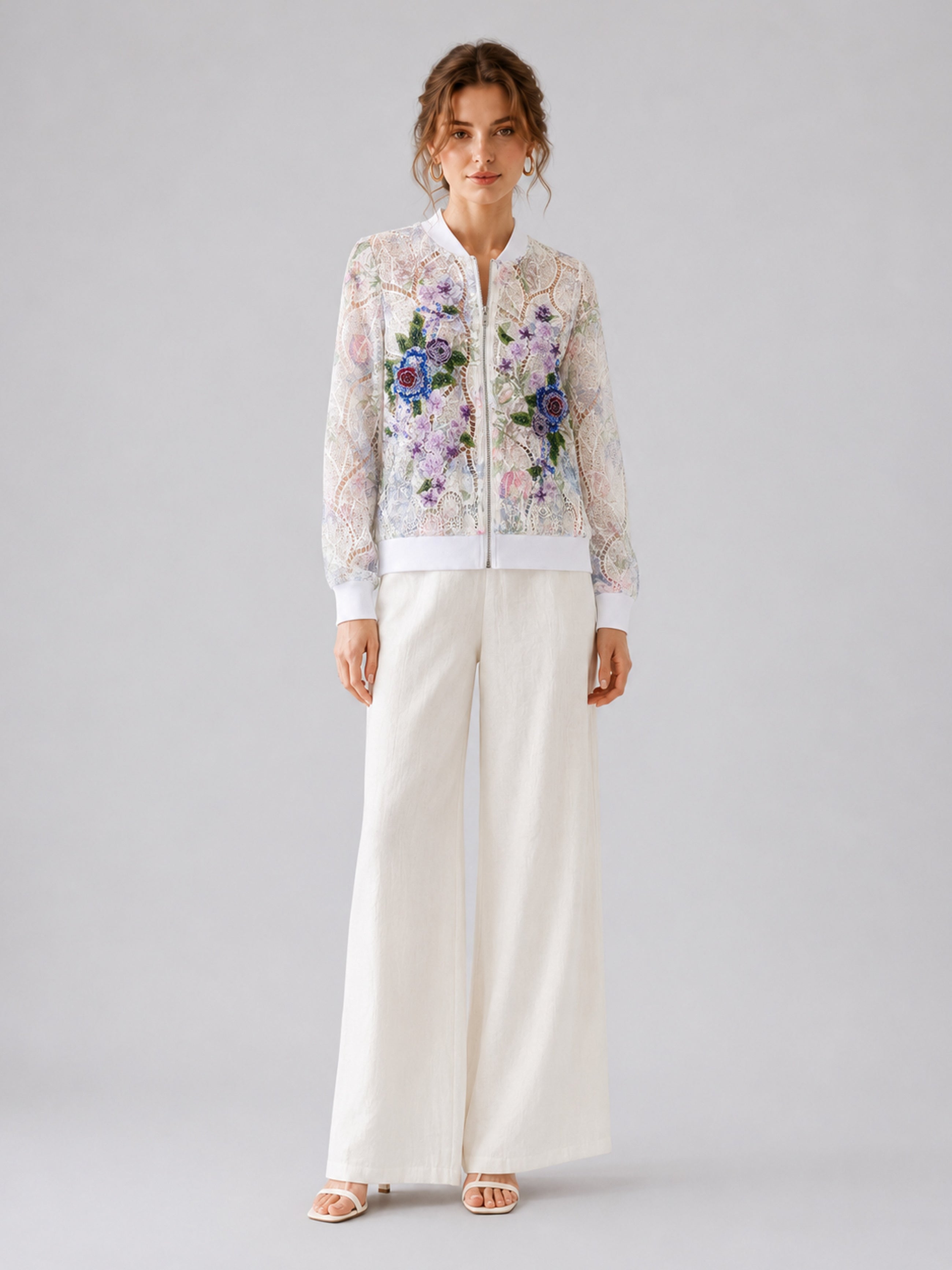 A woman stands against a plain background wearing Social Queen’s Casual Wide-Leg Pants in white, paired with white sandals and a sheer floral embroidered blouse.