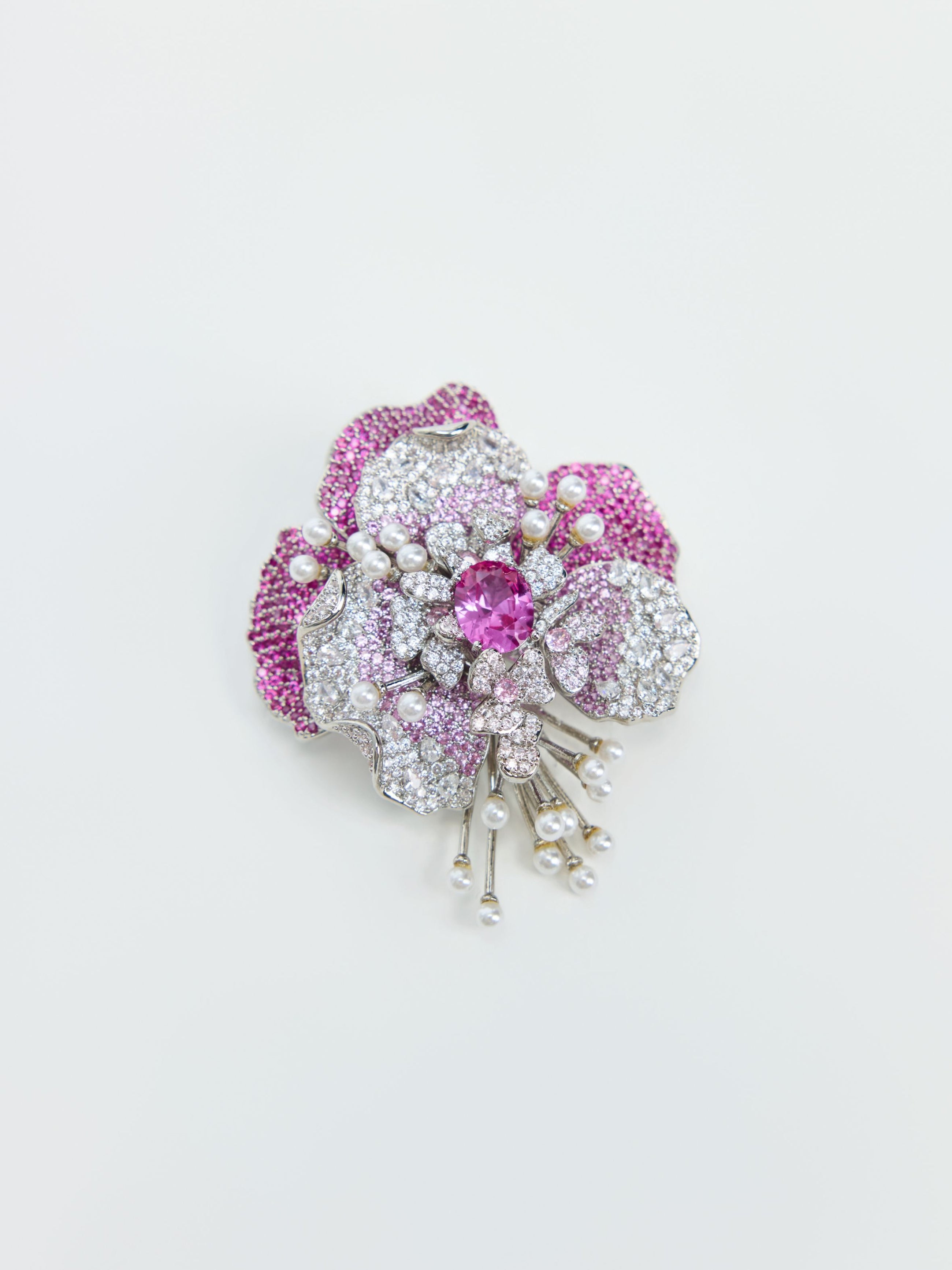 The Social Queen Gradient Peony Rhinestone Brooch, shaped like a flower and adorned with pink and white gemstones along with pearl accents, is displayed against a plain white background.