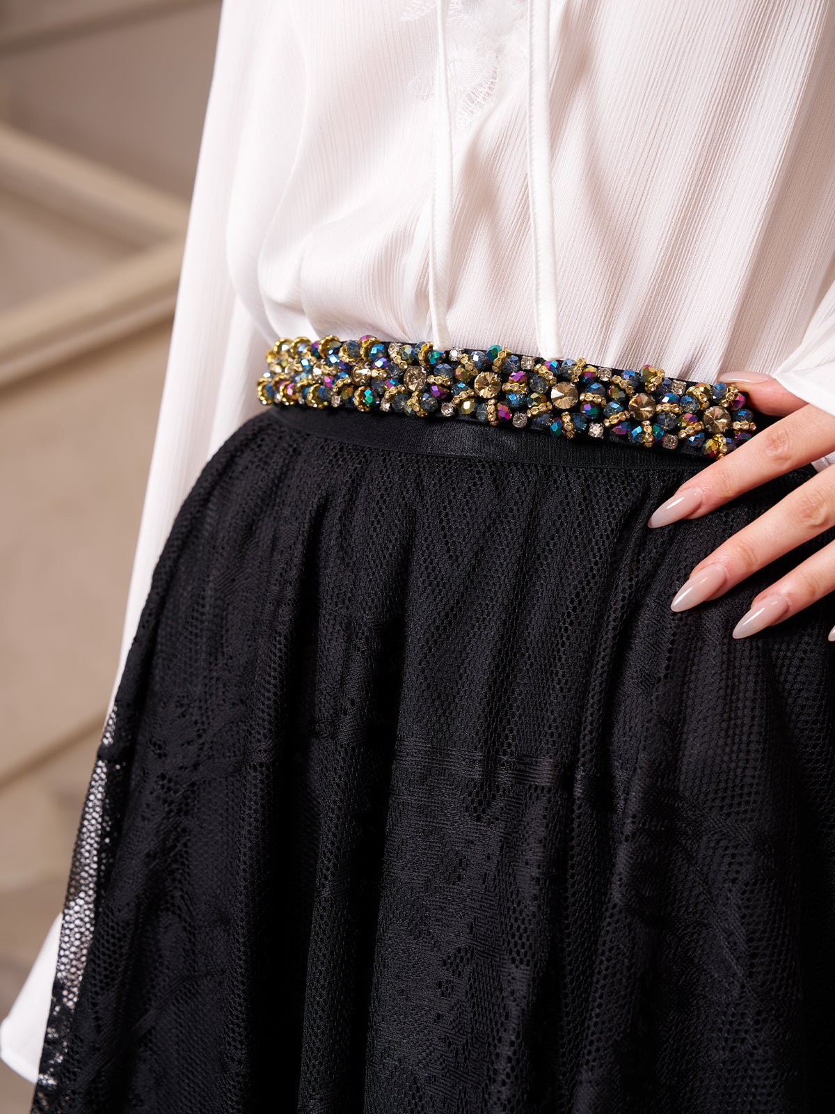 A person wearing a white blouse, a Social Queen Jacquard Lace A-Line Midi Skirt in black, and a decorative belt with colorful beads and gems.
