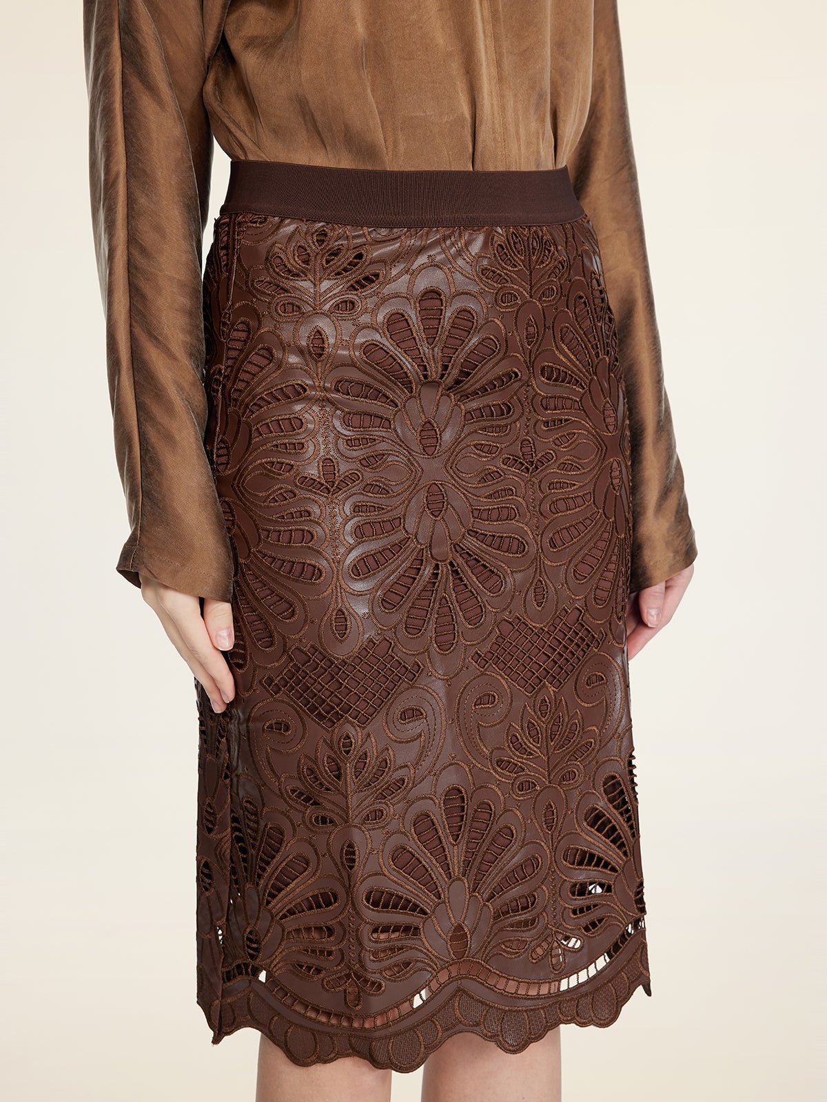 A person wears the Social Queen Openwork Embroidered Leather Skirt with a brown, long-sleeved blouse; the skirt features intricate embroidery and a wavy hem.