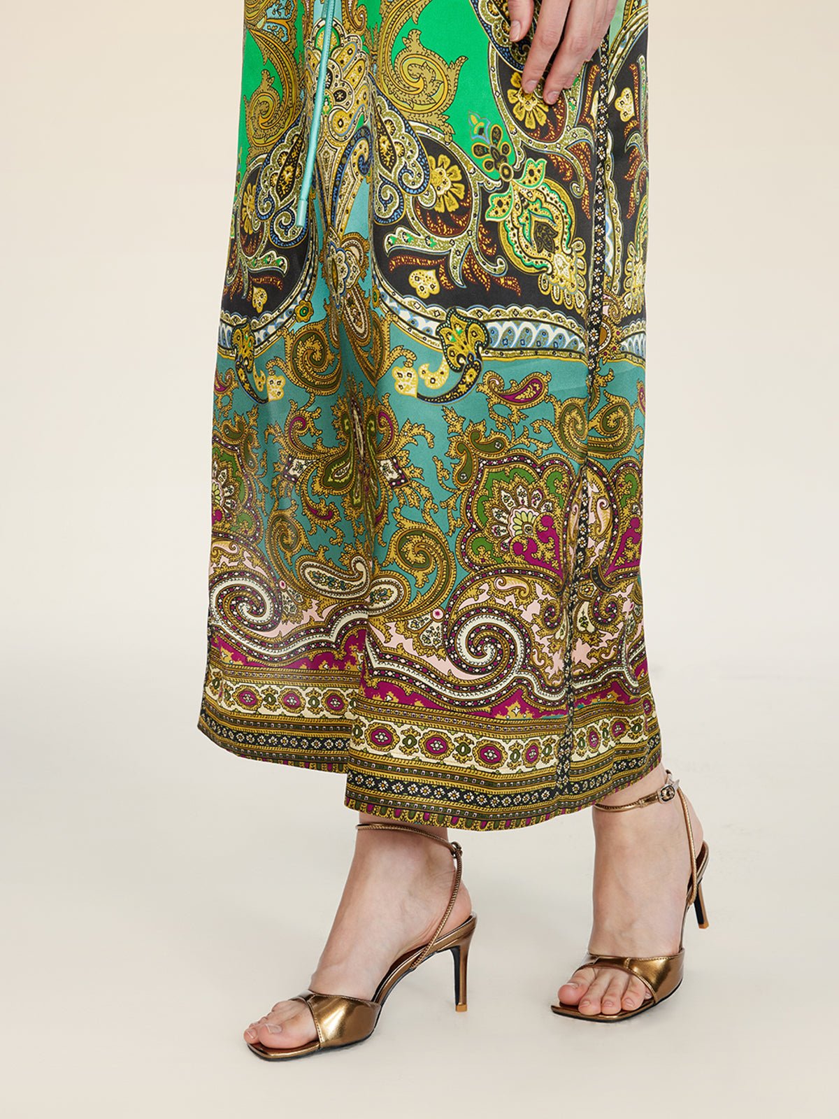 A person in the Social Queen Paisley Printed Silk Satin Dress and metallic open-toe heels stands against a light background.