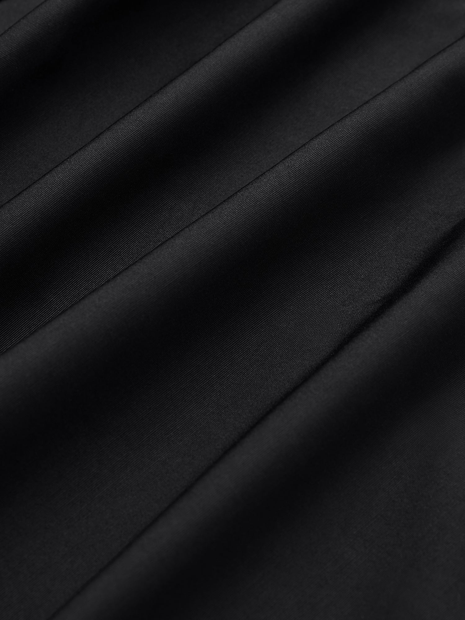 Close-up of smooth black fabric with diagonal folds and soft texture, showcasing the couture craftsmanship of the Pearl & 3D Floral Couture Cape by Social Queen.