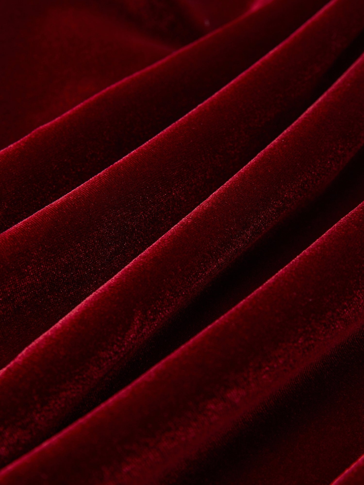 Close-up of rich red velvet fabric with a soft, smooth finish and neat folds from the Pearl & Crystal Velvet Blazer by Social Queen—ideal for a wedding guest outfit.