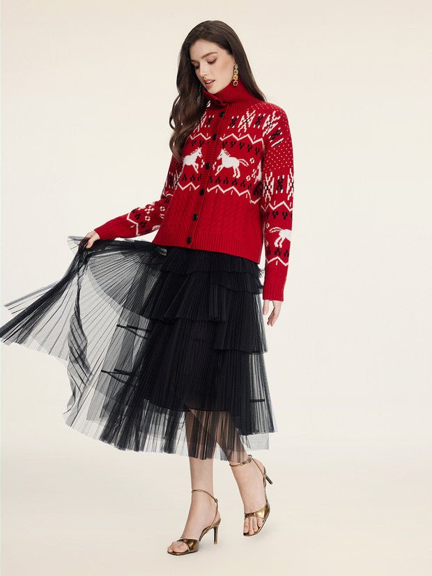 A woman wears the Social Queen Playful Motif 100% Wool Cardigan, featuring vintage-inspired designs, paired with a black tiered tulle skirt and gold high-heeled sandals, standing against a plain background.