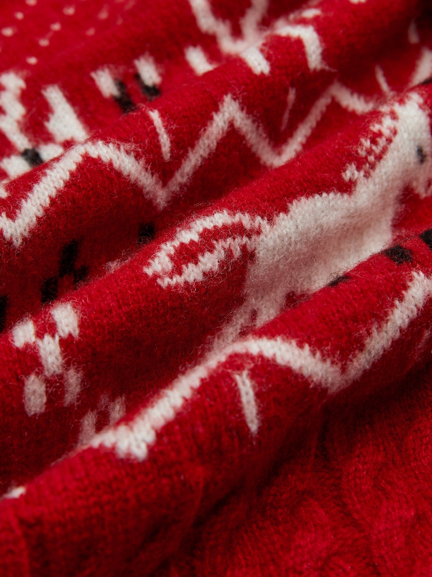 Close-up of the Playful Motif 100% Wool Cardigan by Social Queen, showcasing red and white knitted zigzag and geometric vintage-inspired patterns with a soft, textured finish and visible fibers.