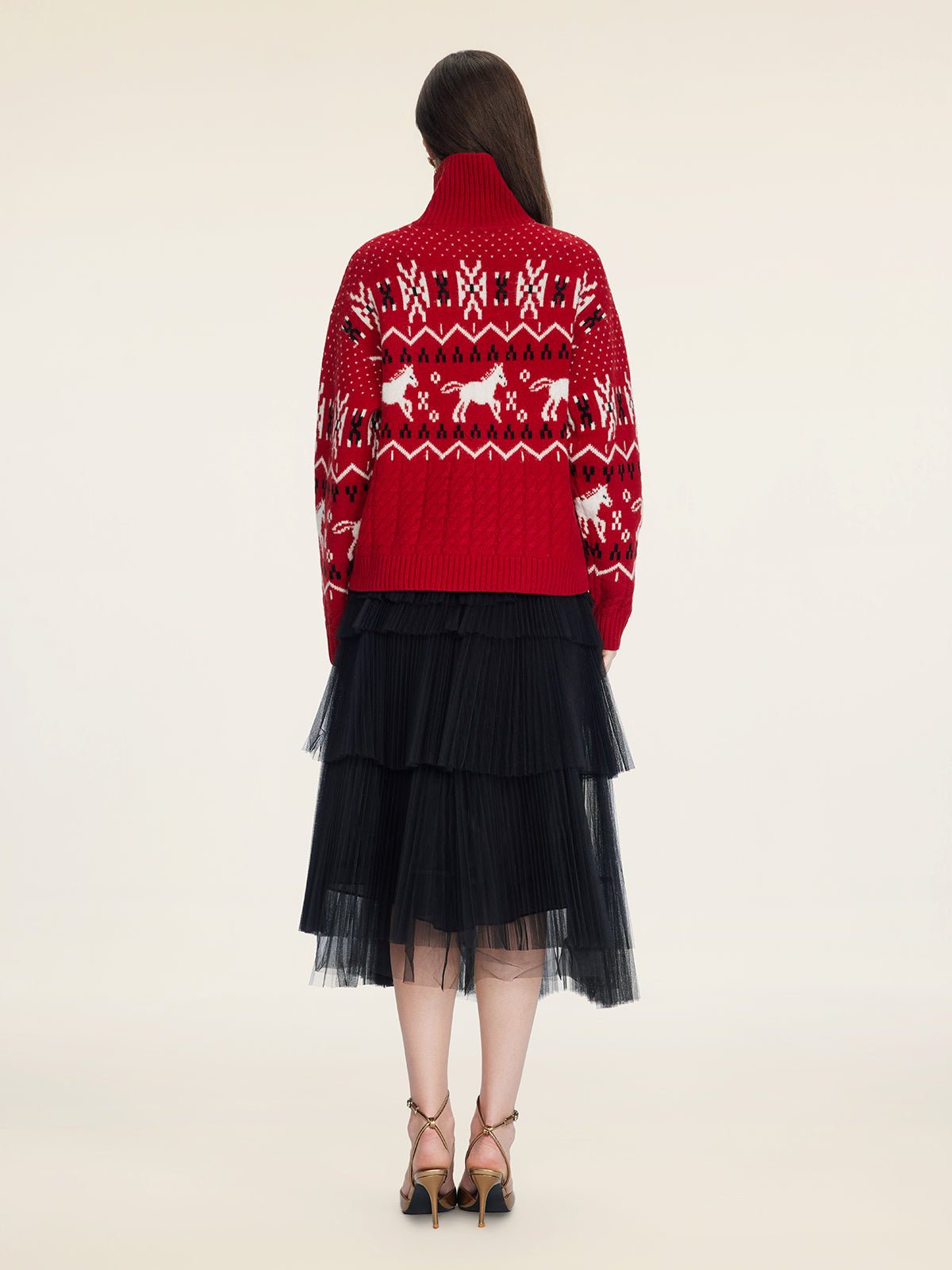 A person faces away, wearing the Social Queen Playful Motif 100% Wool Cardigan in red and white, paired with a black layered tulle skirt and beige high-heeled sandals against a plain background.