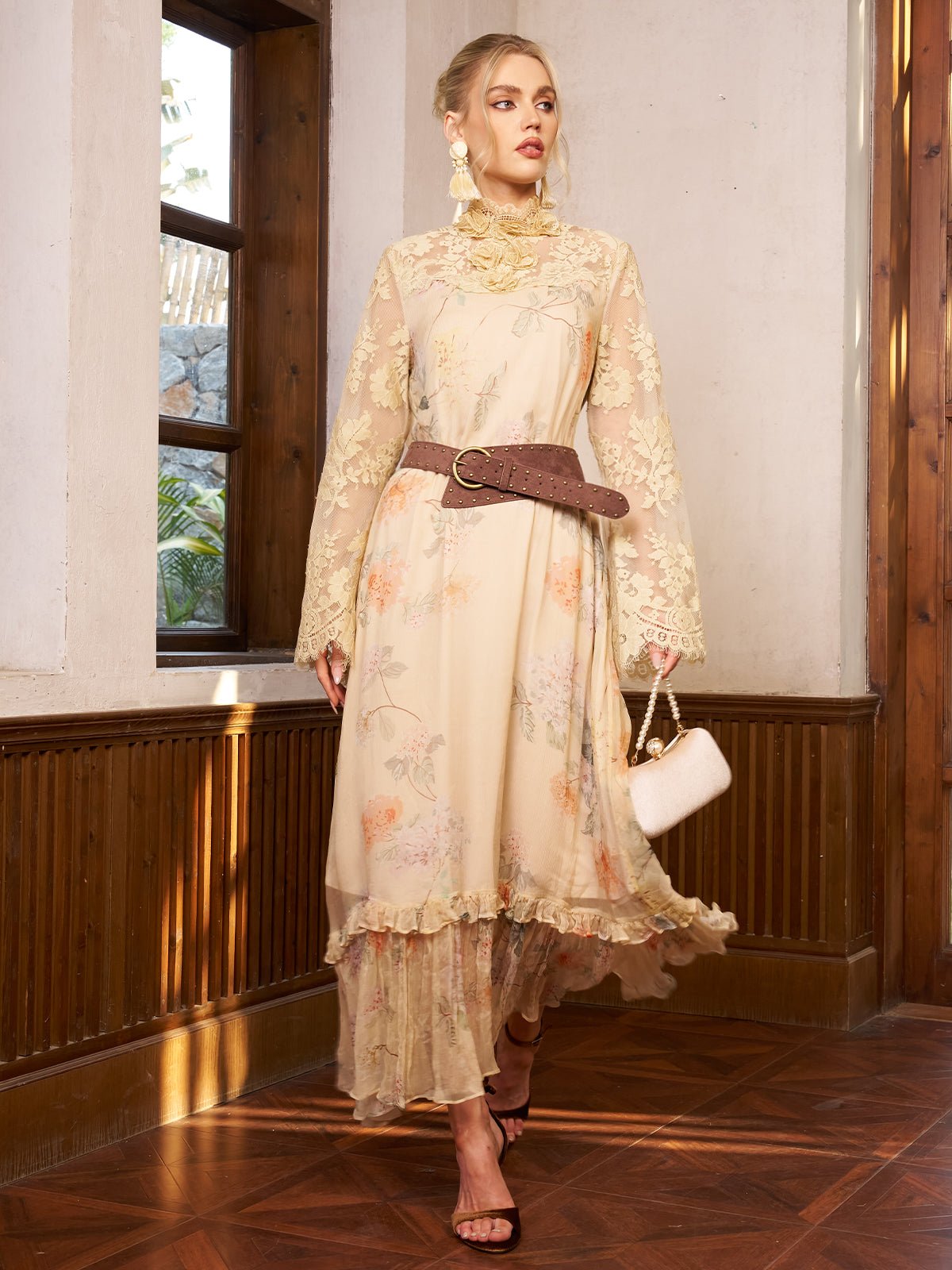 A woman wears the Social Queen Silk Floral & Bird Print Lace Dress with a wide brown belt, beige heels, and a small white handbag, standing indoors by wood-paneled walls.