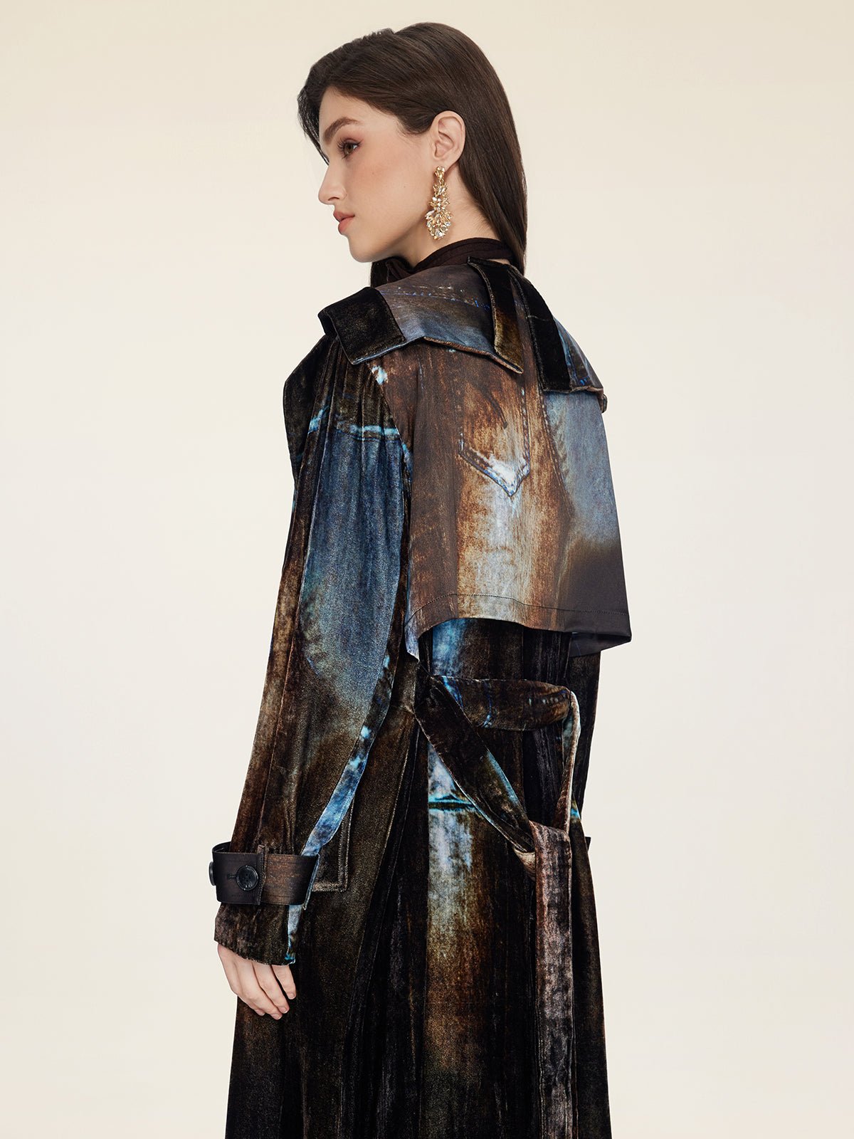 A woman in profile wears the Social Queen Velvet Gradient Tie-Waist Trench Coat with large cuffs and statement earrings, standing against a plain light background.