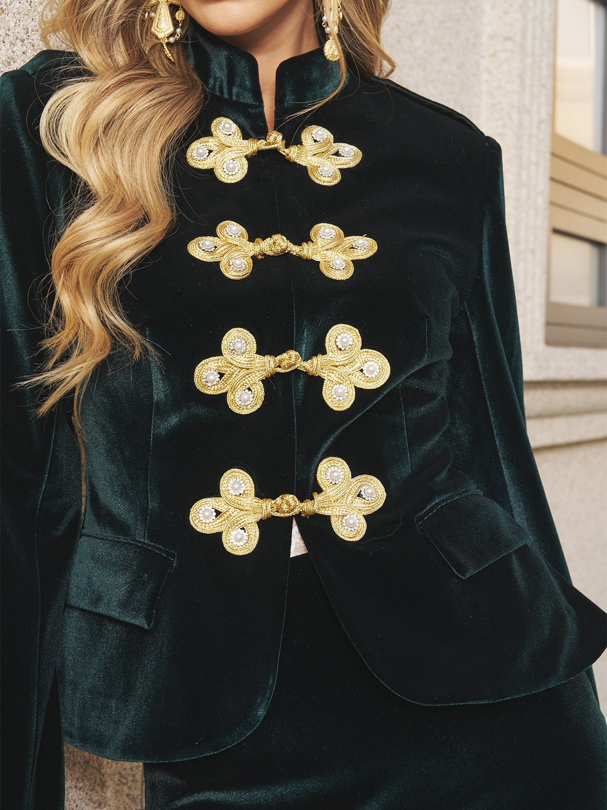 Close-up of a person wearing the Social Queen Velvet Knot-Button Jacket—an emerald velvet blazer with ornate gold knot buttons—making it a stylish choice for wedding guests.