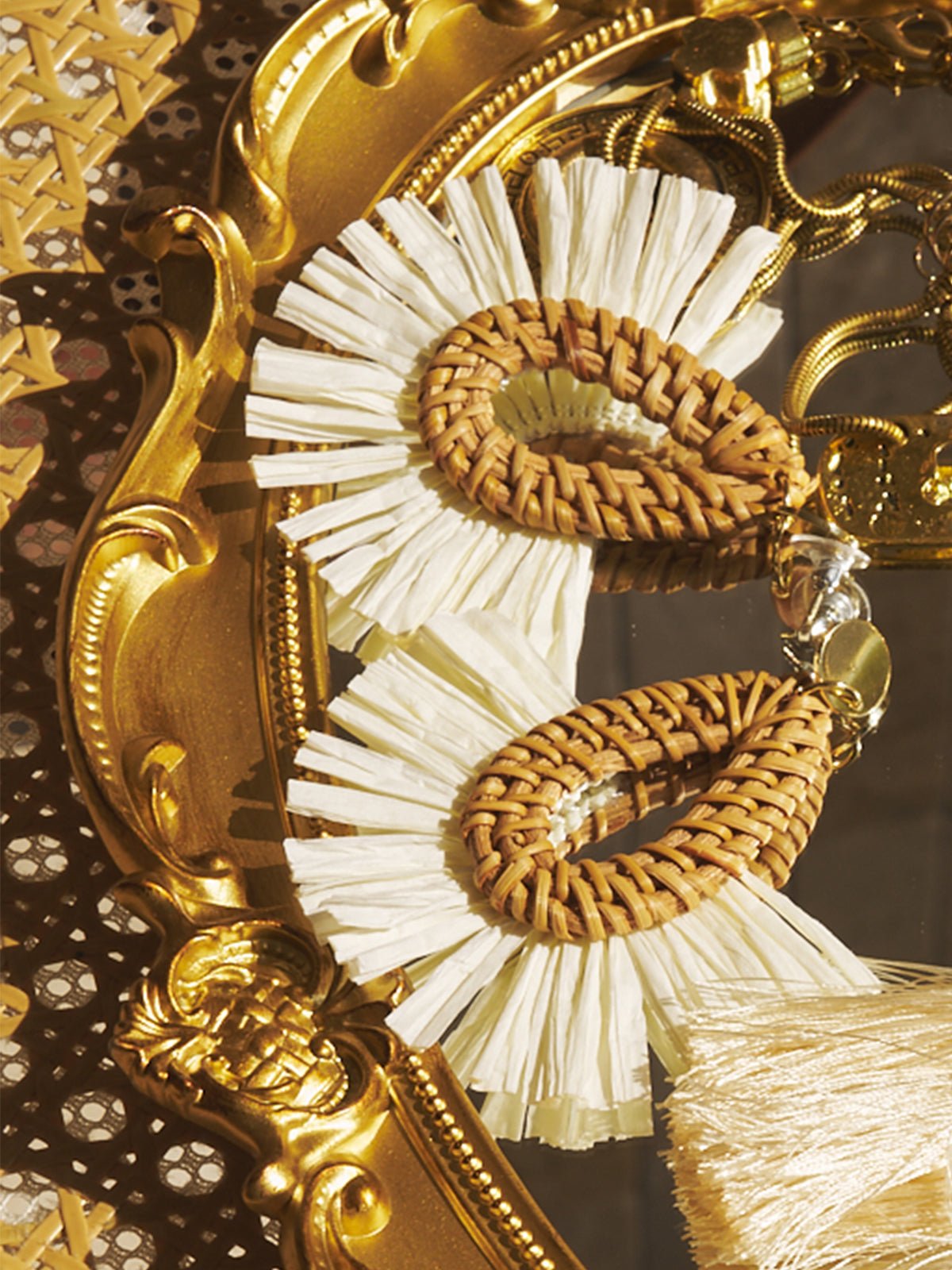 Social Queen’s Woven Fan-Shaped Earrings feature cream fringes and floral cutouts, elegantly displayed on an ornate gold tray.