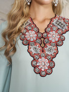 Close-up of a woman wearing the Social Queen 100% Mulberry Silk Feather Limited Dress in light blue, featuring intricate floral beadwork and embroidery at the neckline. Only her neck, part of her chest, and hair are visible.