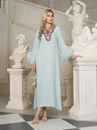 A woman in a light blue dress with feathered sleeves and floral neckline detail stands in a classical marble hall with white statues.