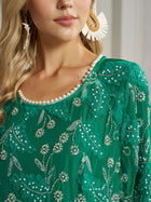 A woman in the Social Queen 100% Silk Beaded Embroidery Dress, detailed with floral beading and pearls at the neckline, pairs it with statement fringe earrings—an elegant choice for a wedding guest.