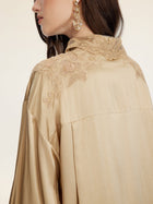 A woman wears the Social Queen 100% Silk Embroidered Lace Satin Blouse, featuring hand-embroidered lace on the collar and shoulder, paired with statement gold earrings.