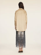 A person stands facing away, wearing the Social Queen 100% Silk Embroidered Lace Satin Blouse in beige, paired with a sequined silver fringe skirt and strappy heels against a plain light background.