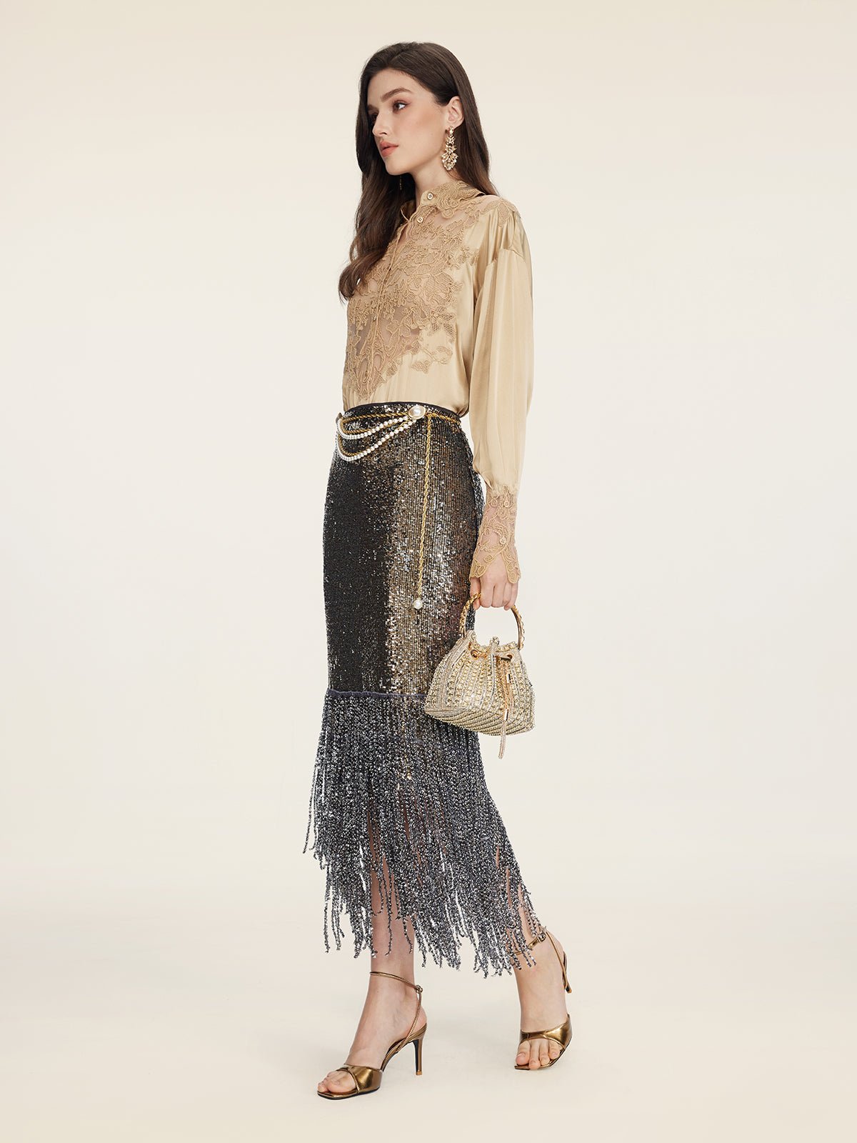 A woman in profile wears the Social Queen 100% Silk Embroidered Lace Satin Blouse, a black sequin fringe skirt, gold heels, statement earrings, and carries a small gold handbag with pearl details.