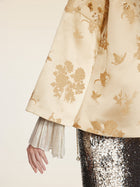 Wearing Social Queen’s 100% Silk Floral Embroidered Satin Jacket, a person shows off one arm against a neutral background, with the floral embroidery and satin finish adding elegance to their look.