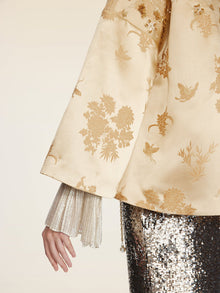 Wearing Social Queen’s 100% Silk Floral Embroidered Satin Jacket, a person shows off one arm against a neutral background, with the floral embroidery and satin finish adding elegance to their look.