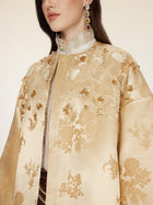 A woman wears the Social Queen 100% Silk Floral Embroidered Satin Jacket, featuring intricate floral embroidery, styled with a ruffled high-neck blouse and dangling gemstone earrings.