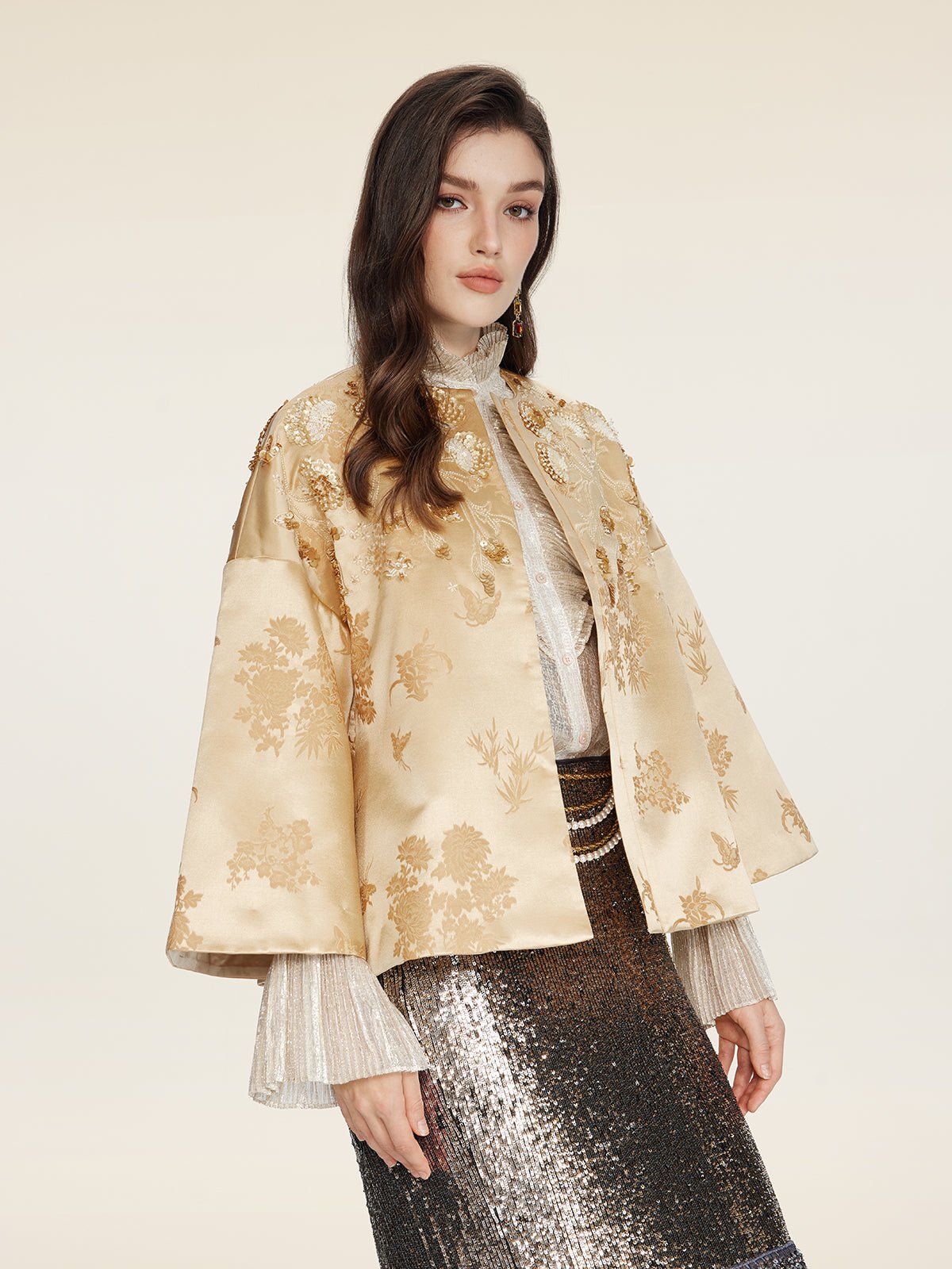A woman models the Social Queen 100% Silk Floral Embroidered Satin Jacket over a sheer blouse and silver sequined skirt, posing against a plain light background.