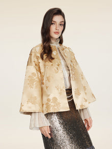 A woman models the Social Queen 100% Silk Floral Embroidered Satin Jacket over a sheer blouse and silver sequined skirt, posing against a plain light background.