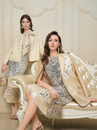 Two women wear Social Queen 100% Silk Metallic Ribbon-Tie Blouses with sequins and puff sleeves, posing on an ornate white and gold sofa against a cream wall.