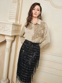 A woman embodies French vintage elegance in the Social Queen 100% Silk Retro Floral Appliqué Satin Blouse and a black sequin fringe skirt, posing indoors against a decorative cream-colored wall and fireplace.