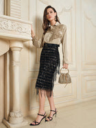 A woman radiates French vintage charm indoors in the Social Queen 100% Silk Retro Floral Appliqué Satin Blouse, paired with a black fringed skirt, black strappy heels, and a beaded handbag as she leans on a decorative mantelpiece.