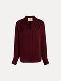 The Social Queen 100% Silk Satin Wrap V-Neck Blouse in burgundy features long sleeves, pleated shoulders, buttoned cuffs, and a cross-front design. Shown on a plain white background, it's ideal for versatile styling.