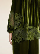 A person wears the Social Queen 100% Silk Velvet Lace-Panel Blouse, featuring hand-stitched lace on the sleeve and hem. Only the back of the upper body and part of one arm are shown.