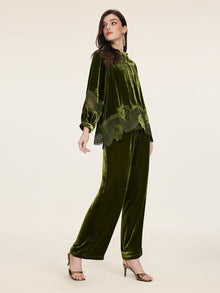 A woman models the Social Queen 100% Silk Velvet Lace-Panel Blouse in olive green, styled with matching pants and heels, radiating vintage luxe against a simple light background.