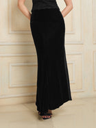 A person stands indoors against a beige paneled wall, exuding vintage-inspired elegance in the Social Queen 100% Silk Velvet & Tulle Mermaid Skirt paired with black sandals.